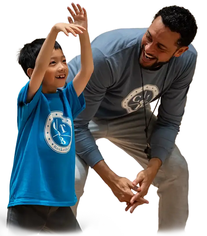 A coach teaching a young boy how to shoot a basketball